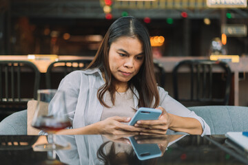 Portrait of beautiful asian woman with smartphone, relaxing in cafe, sitting and enjoying coffee while using mobile phone remote work online