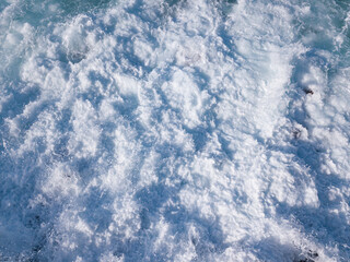 Foam from the waves crashing on a rocky beach in southern Tenerife. Wallpaper, copy space