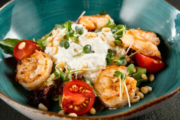 Salad with grilled shrimp and stracciatella cheese, accompanied by greens and cherry tomatoes in a turquoise bowl