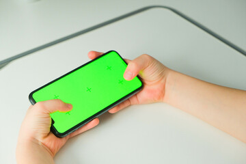 Close-up of children's hands holding smartphone with green screen