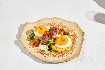 A beautifully arranged plate of potato pancakes with roast beef and a sunny side up egg, ready for breakfast