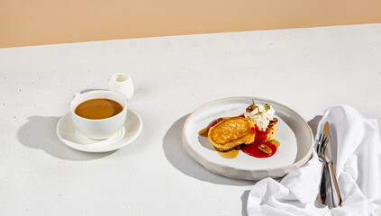 Pancakes topped with cream cheese, berry sauce, and mango, accompanied by coffee with milk