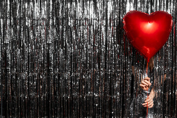 Single red big heart metallic helium balloon for birthday or Valentine's Day isolated on a tinsel...
