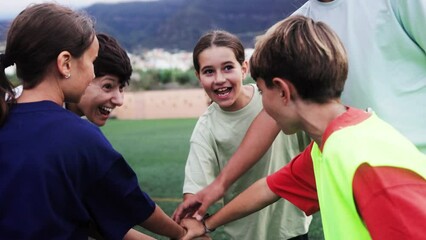 Sport group of kids and coach trainer stacking hands in school field. Children motivation before game or practice - Powered by Adobe