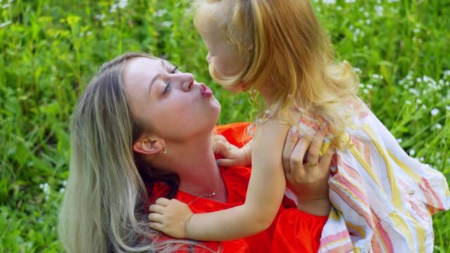 Happy emotions happiness mother hugs her daughter in the grass. Smiles are parental love. High quality 4k footage
