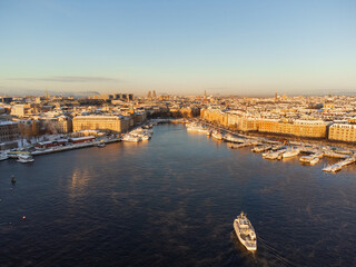 Fototapeta premium A ferry commuter boat leaving Gamla Stan, the old town, at sunrise, fuming sea, snow and ice. Bright sunshine.