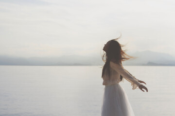 vital young woman with her hair blowing in the wind in front of the lake, concept of freedom and youth - 706563103