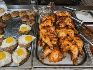 Fried chicken legs are on the counter, a patty with a fried egg, a distribution line in the cafeteria, a quick meal in a cafe.