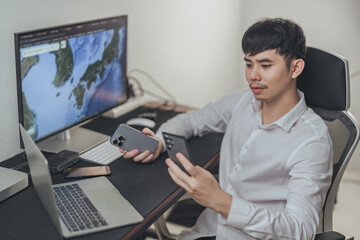 Young asian businessman using smartphones and computers. - obrazy, fototapety, plakaty