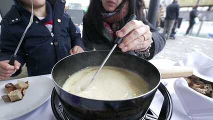 Mother and Child Enjoying Swiss Fondue on Vacation, close-up of hot traditional European food at...