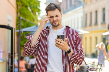 Caucasian brunette man use smartphone typing browsing, loses becoming surprised sudden lottery...
