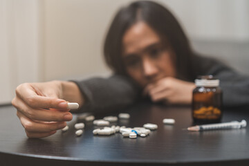 Anti drugs, drug addict asian young woman hand holding pills, medicament with narcotic syringe on...