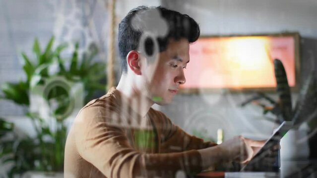 Animation of media icons and binary coding over asian man using tablet