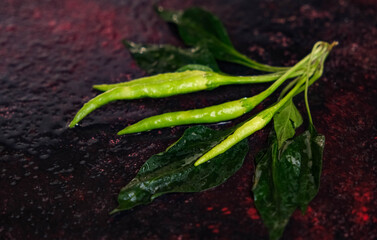 Green peppers with leaves on dark background. Healthy eating, vegan food concept