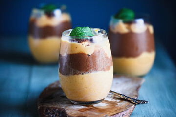 Delicious vegan mango chocolate pudding garnished with mint leaves. Selective focus with blurred background.