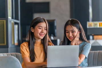 Weekend Out-of-Office Collaboration. Two young Asian woman break away from the office, opting for a cozy café to discuss work. 
