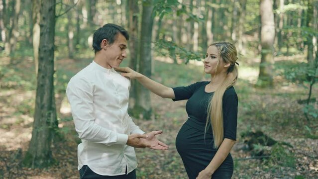 Young pregnant woman and her husband having fun in park. Happy family outdoors. Expecting for firstborn	