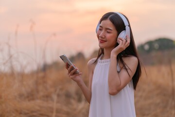 Cute beautiful girl in a meadow field with headphone and phone