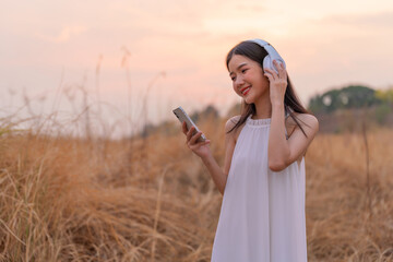 Cute beautiful girl in a meadow field with headphone and phone