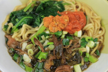 Mie Ayam or Chicken noodle, Popular Indonesian Street Food served in a bowl with sauce and chili sauce