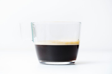 A cup of espresso with crema in transparent glass mug on isolated white background