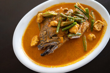 Grouper fish head curry close up in white plates and isolated brown table