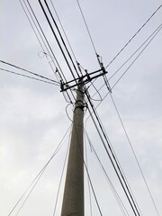 Electric pole with tangled cables, photographed from below in the afternoon