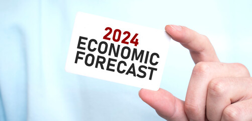 Man in blue sweatshirt holding a card with text 2024 ECONOMIC FORECAST,, business concept
