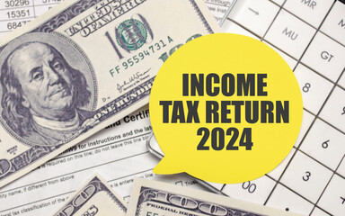 INCOME TAX RETURN 2024 on yellow sticker with pen and calculator