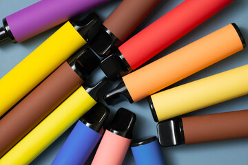 used a variety of disposable electronic cigarettes. Many colorful vapes lie on a gray background