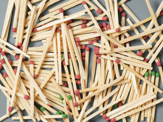 scattered wooden matches with red and green heads on gray paper. Deforestation symbol