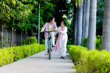 Fototapeta premium Mother helping daughter in cycling in Outdoor Garden, Mother and daughter Bonding ,