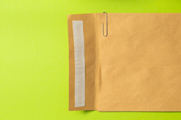 kraft envelope with a paper clip on a green background. an envelope made of recycled paper