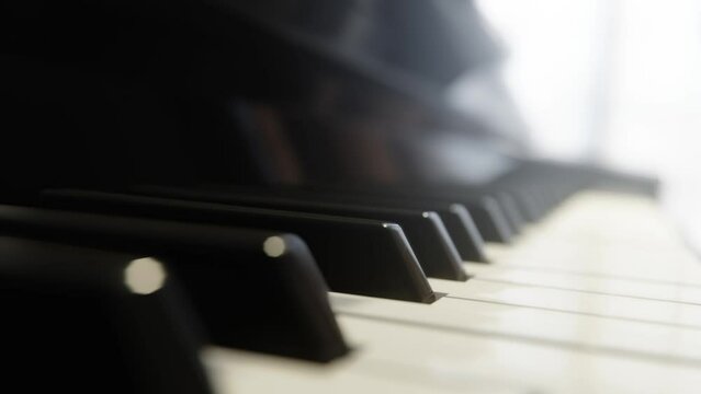 Piano keyboard close-up forward panning in warm light. Background for classical musical, concert show, song or music theatre orchestra performance. Shallow depth of focus