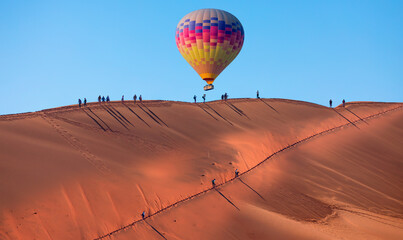 Hot air balloon flying over Dead trees in Dead Vlei - Sossusvlei, Namib desert, Namibia