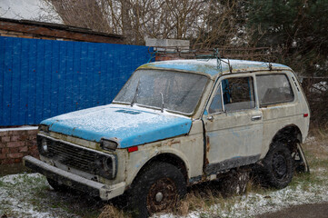 Obraz premium Old rusty, broken, abandoned car near the blue fence