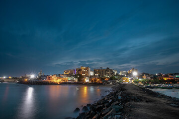 cloudy sky blue hour of the port city Kanyakumari  tamilnadu India with street light and reflections on sea waters