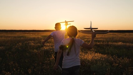 Child, Boy Girl dream of flying into future. Happy children run with toy plane across field,...