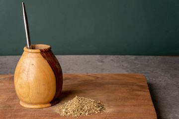 Calabash with Yerba Mate tea and bombilla  on wooden table on light gray background.