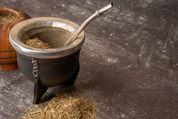 Healthy infused beverage, classic Yerba Mate tea in a gourd with bombilla and grass on a light gray background.