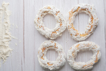 Rosquete, traditional Bolivian snack made of flour and dipped in cream. 4 rosquetes on a white wooden table