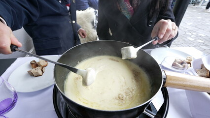 Swiss fondue - closeup of hands eating bread with cheese at restaurant meal, traditional European food during winter season, child and mother