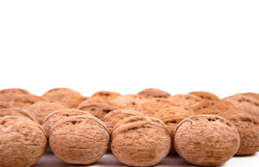 Scattered whole walnuts lie on a white background. Backgrounds and textures. Isolate.