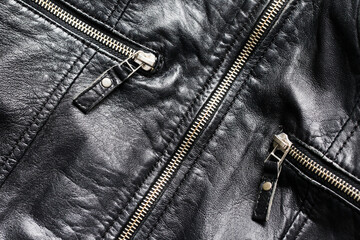 Black leather jacket background. Grunge autumn clothing. Winter fashion texture. Closed fastener...