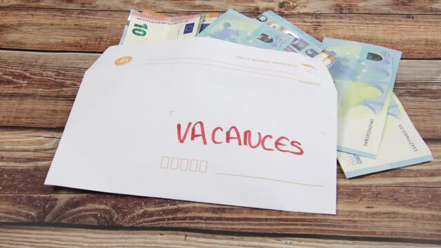 enveloppe rempli de billets de banque avec un papier avec écrit dessus "vacances" en français
