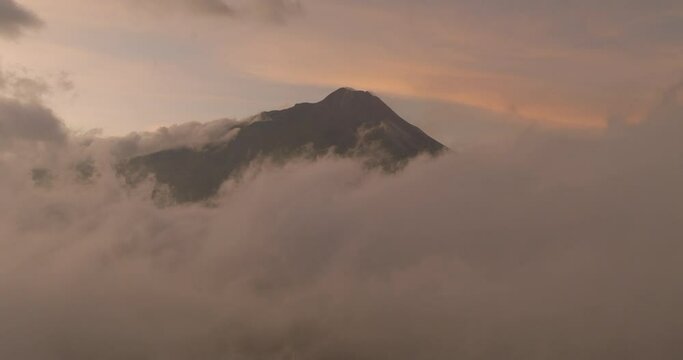 Aerial Shot Of Volcanic Mountain Peak Amidst Fluffy Clouds, Drone Flying Forward During Sunset - Java, Indonesia