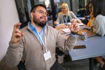 Fototapeta premium Man hoping for something with his fingers crossed while his colleagues are in the back