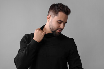 Handsome man in stylish black sweater on grey background