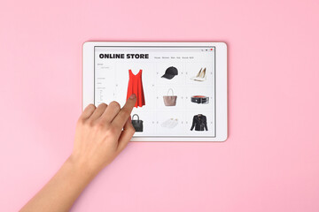 Woman with tablet shopping online on pink background, top view