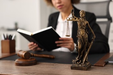 Notary with notebook at workplace in office, focus on statue of Lady Justice